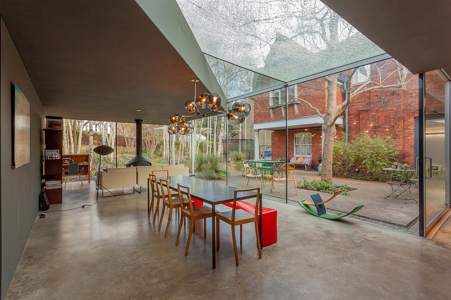 Modern kitchen with two glass walls and large skylight. Glass walls give view to an outdoor patio and tree.